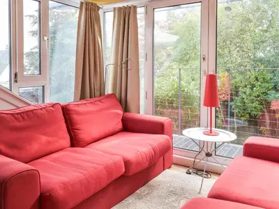 a living room with a red couch in front of a window at Tigh Nam Muc in Loanhead