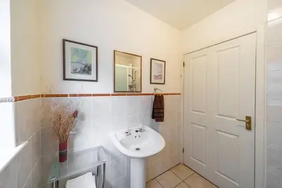 a white bathroom with a sink and a mirror at Earnside Cottage in Comrie