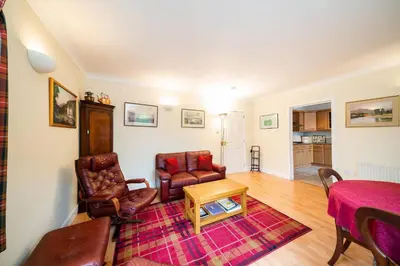 a living room with two chairs and a table at Earnside Cottage in Comrie