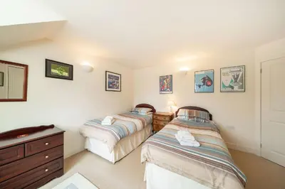 a bedroom with two beds and a dresser at Earnside Cottage in Comrie