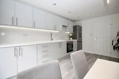 a kitchen with white cabinets and a table and chairs at Katie's house in Cumbernauld