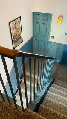 a stairway with a blue door and a stair railing at Custom House Hotel in Bowling