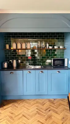 a kitchen with blue cabinets and a brick wall at Custom House Hotel in Bowling