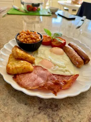 a plate of food with meat and sausage and beans at FINN VILLAGE Loch Lomond Villa - THE BLACK ROOM with Private Jacuzzi-Style Bath in Drymen