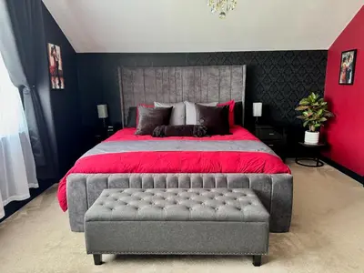 a bedroom with a large bed with a red bedspread at FINN VILLAGE Loch Lomond Villa - THE BLACK ROOM with Private Jacuzzi-Style Bath in Drymen