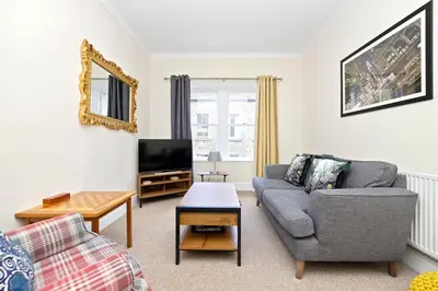 a living room with a couch and a tv at JOIVY Modern Flat on Rose Street in Edinburgh