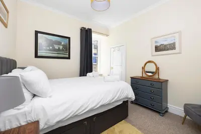 a bedroom with a bed and a dresser and a window at JOIVY Modern Flat on Rose Street in Edinburgh