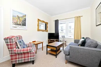 a living room with two chairs a couch and a tv at JOIVY Modern Flat on Rose Street in Edinburgh
