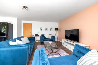 a living room with blue couches and a flat screen tv at JOIVY Modern 2 bed flat near Murrayfield Stadium in Edinburgh