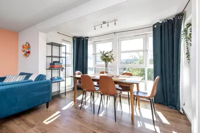 a dining room with a table and chairs and a blue couch at JOIVY Modern 2 bed flat near Murrayfield Stadium in Edinburgh