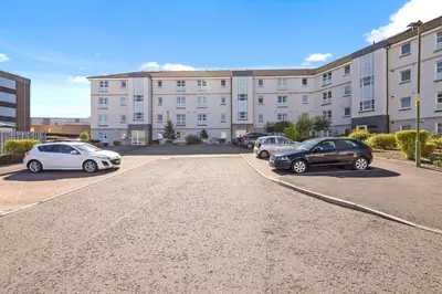 a parking lot with cars parked in front of a building at JOIVY Modern 2 bed flat near Murrayfield Stadium in Edinburgh