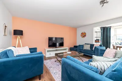 a living room with blue couches and a tv at JOIVY Modern 2 bed flat near Murrayfield Stadium in Edinburgh