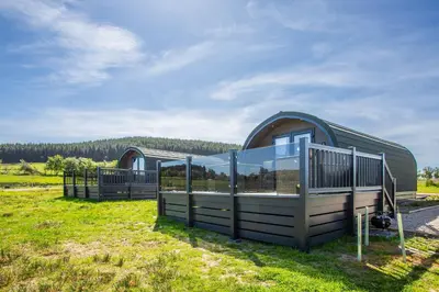 a building with a fence in a field at Kings Caves Glamping in Torbeg