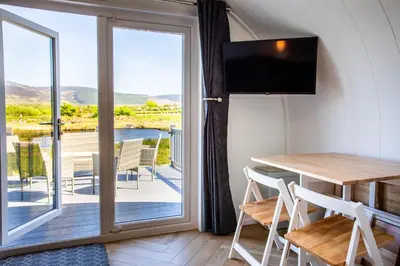 a room with a table and a balcony with a view at Kings Caves Glamping in Torbeg