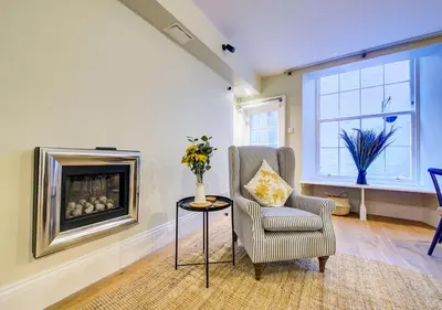 a living room with a chair and a fireplace at Super central Edinburgh Castle basement in Edinburgh