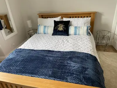 a bed with a blue and white comforter and pillows at Number 79, Cosy Central Helensburgh 1 Bedroom, ground floor pet friendly, garden in Helensburgh