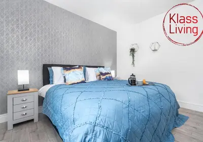 a bedroom with a bed with a blue comforter at Sanderson Apartment by Klass Living Uddingston in Uddingston