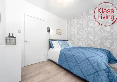 a bedroom with a bed with a blue comforter at Sanderson Apartment by Klass Living Uddingston in Uddingston