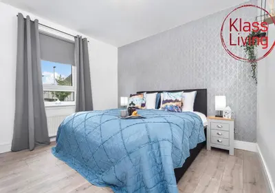 a bedroom with a bed with a blue comforter and a window at Sanderson Apartment by Klass Living Uddingston in Uddingston