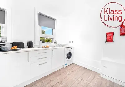 a kitchen with white cabinets and a washing machine at Sanderson Apartment by Klass Living Uddingston in Uddingston