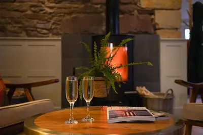 two wine glasses sitting on a table with a magazine at The Woodside in Doune
