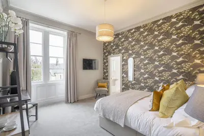 a bedroom with a large bed and a wall of wallpaper at The Woodside in Doune