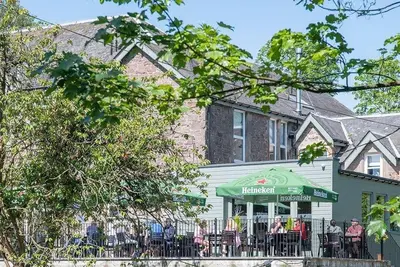 a group of people sitting at a table in front of a house at The Woodside in Doune