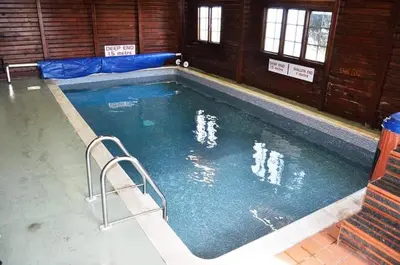 a large swimming pool with two people in the water at 47 Lochview in Stranraer