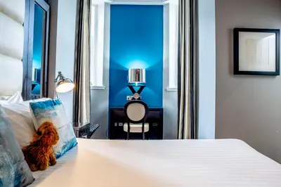 a teddy bear sitting on a bed in a bedroom at Colessio in Stirling