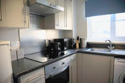a kitchen with white cabinets and a sink at The Nelson - Spacious City Property and Free Parking in Glasgow