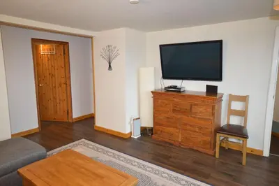 a living room with a flat screen tv on a dresser at Ardura Apartment No 2 in Oban