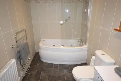 a bathroom with a white tub and a toilet at Ardura Apartment No 2 in Oban