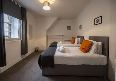 a bedroom with a large bed with orange pillows at George Street Apartment in Oban