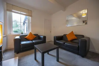 a living room with two leather chairs and a table at George Street Apartment in Oban