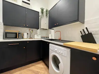 a kitchen with black cabinets and a washing machine at The Haven in Greenock