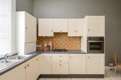 a white kitchen with white cabinets and a sink at 2 Bed Old Town Apartment - Next To Castle in Edinburgh