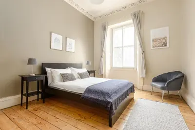 a bedroom with a bed and a chair and a window at 2 Bed Old Town Apartment - Next To Castle in Edinburgh