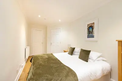 a bedroom with a white bed with a green blanket at JOIVY Lovely Flats near the City Centre in Edinburgh