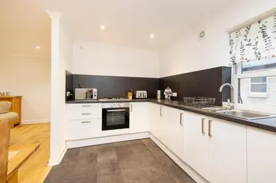 a kitchen with white cabinets and a sink at JOIVY Lovely Flats near the City Centre in Edinburgh