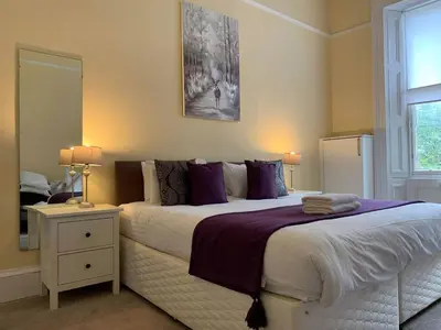 a bedroom with a large bed with purple pillows at JOIVY Adorable flat near West End in Edinburgh