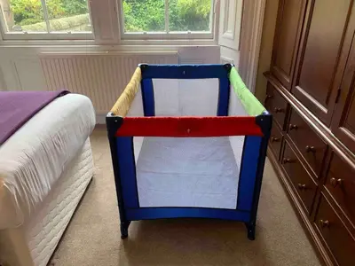 a colorful crib sitting next to a bed in a bedroom at JOIVY Adorable flat near West End in Edinburgh