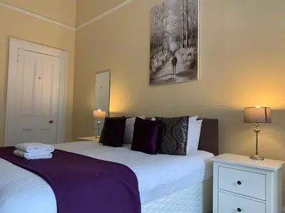 a bedroom with two beds with purple sheets and two lamps at JOIVY Adorable flat near West End in Edinburgh