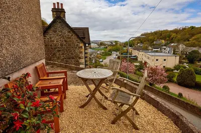 a patio with a table and chairs on a balcony at Campbells Loft in Oban