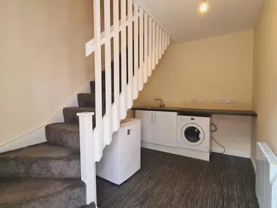 a laundry room with a washer and dryer and stairs at Campbells Loft in Oban