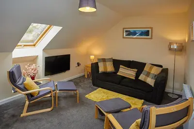 a living room with a black couch and chairs at Campbells Loft in Oban