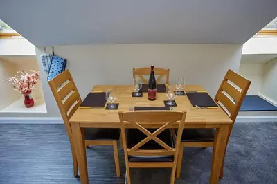 a wooden table with chairs and a bottle and glasses at Campbells Loft in Oban