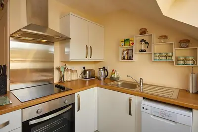 a kitchen with white cabinets and a stainless steel appliances at Campbells Loft in Oban