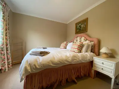 a bedroom with a large bed and a night stand at Lochs Lodge, Glenlyon, Perthshire in Bridge of Balgie
