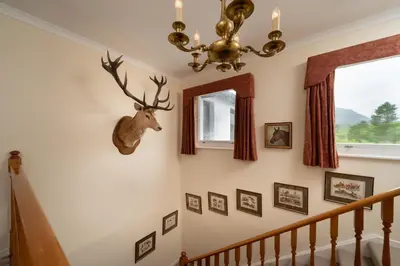 a stairway with a deer head on the wall at Lochs Lodge, Glenlyon, Perthshire in Bridge of Balgie