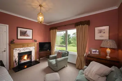 a living room with a fireplace and a tv at Lochs Lodge, Glenlyon, Perthshire in Bridge of Balgie